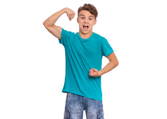 Wall Mural - Portrait of funny teen boy raised his hands and shows biceps, isolated on white background. Handsome teenage young boy shows biceps, looking at camera in amazement. Happy strong child flexing biceps