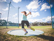 © Dewald - Wide angle action photo of a female discus athlete throwing a discus
