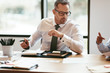 © Flamingo Images - Mature businessman going over paperwork during a boardroom meeti