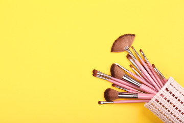 Wall Mural - Set of makeup brushes in basket on yellow background