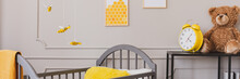 Panoramic View Of Cute Yellow And Grey Baby Bedroom With Teddy Bear And Clock On Black Wooden Shelf