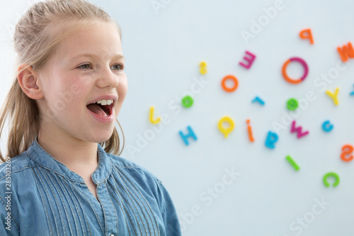 Fotomural Cute blond little girl opening her mouth during speech therapy, copy space on th