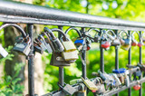 Fototapeta Tęcza - Hinged love locks hanging on a bridge