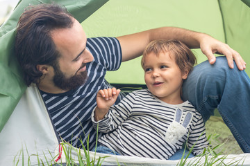 Father's day. Happy family on vacation, camping, in a tent. Joyful father and son travel together in nature, pitched a tent in the camping. father and son having fun in the fresh air, at sunset