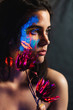 © Alberto Ortega/ADDICTIVE STOCK - Portrait of beautiful young woman covered with luminous paint on face holding a flower and looking away.