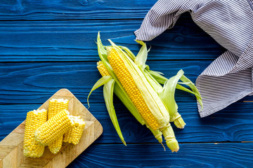 Wall Mural - Ripe corn on cobs on blue wooden table background top view