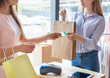 Female assistant holding purchases and accepting credit card