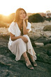 © Victor Bordera/ADDICTIVE STOCK - Beautiful young female model sitting and posing on rock looking at camera