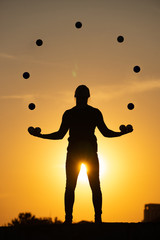 Wall Mural - Silhouette of a man Juggling with Balls at Sunset