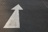 Fototapeta  - Closeup of arrow sign on asphalt ground of the parking lot after raining. 