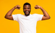 © Prostock-studio - African american man smiling and showing biceps at camera