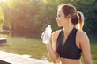 © fotofabrika - Young beautiful woman drinking water during morning jogging in the park