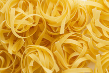 Pasta Background Made Of Dry Uncooked Tagliatelle Nests.