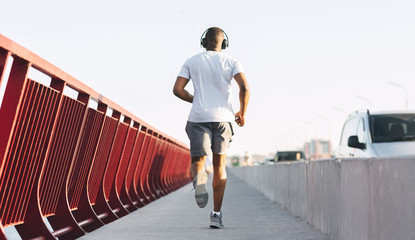 Wall Mural - Sporty african american guy running along the bridge