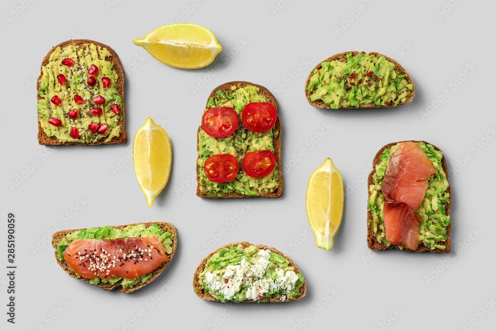 Different tasty avocado toasts on grey background