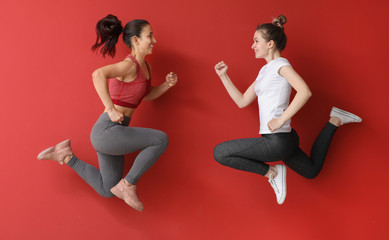 Jumping sporty women on color background