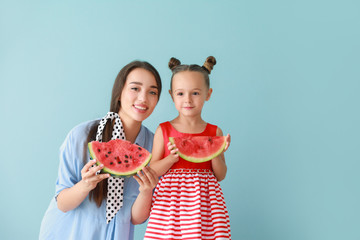 Wall Mural - Beautiful young woman and cute little girl with fresh watermelon on color background