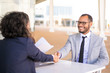 © Mangostar - Successful business people meeting outside and closing deal. Happy business man and woman sitting at table, talking and shaking hands. Deal or success concept