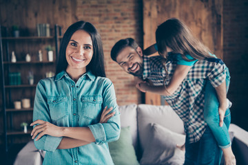 Canvas Print - Portrait of charming woman with her arms crossed smiling and people piggy-backing wearing plaid denim jeans shirt t-shirt indoors