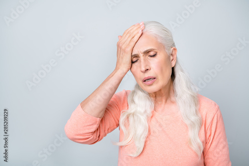 Reaction on magnetic storm hot warm weather and global warming concept. Close up photo of sad upset nervous in bad condition old lady having acute periodical pain isolated grey background