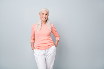 Photo studio shot of optimistic nice pretty with toothy smile old lady posing standing isolated over grey background