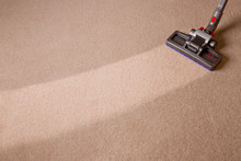 Housekeeper Doing Vacuum Cleaning. Maid Vacuuming The Carpet. Carpet Is Dirty With Cleaned Area.