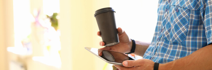 millennial man hold tablet with coffee cup outdoor closeup. internet surfing tablet pc concept