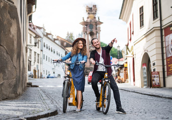 Wall Mural - young tourist couple travellers with electric scooters in small town.