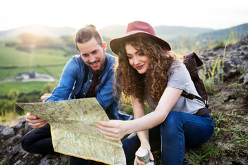 Wall Mural - young tourist couple travellers with backpacks hiking in nature, using map.