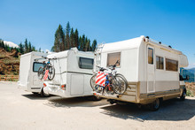 House Camper On The Wheels, Travel In Vacation. Camper With Bicycles On A Camping Site. Caravan Car Summer Holidays By The Sea Sunny Morning