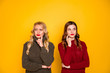 © deagreez - Two minded ladies look empty space holding hand on cheek wear knitted jumpers isolated yellow background