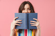© Drobot Dean - Beautiful happy emotional young cute woman posing isolated over pink wall background covering face with book.