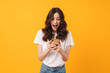© Drobot Dean - Happy shocked emotional young woman posing isolated over yellow wall background using mobile phone.