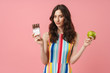 © Drobot Dean - Beautiful woman posing isolated over pink wall background holding apple and chocolate.