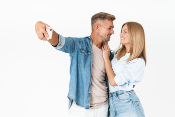 Wall Mural - Portrait of romantic couple man and woman in denim clothing taking selfie photo together on smartphone