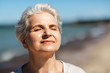 © Syda Productions - people and leisure concept - portrait of happy senior woman enjoying sun on beach