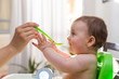 © AlexPhotoStock - Adorable baby eating food. His mother feeds him with a spoon.