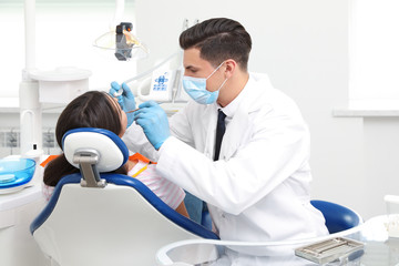 Wall Mural - Professional dentist working with patient in clinic