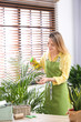© New Africa - Young woman taking care of houseplant indoors. Interior element