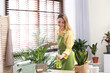 © New Africa - Young woman taking care of houseplant indoors. Interior element