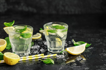 Summer basil lemonade on grey background. Fresh summer cocktail with basil, lemon and ice cubes. Homemade fresh lemonade with lemon and basil. Food and drink concept