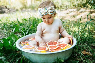 Wall Mural - A little girl bathes in a basin with fruit in the garden