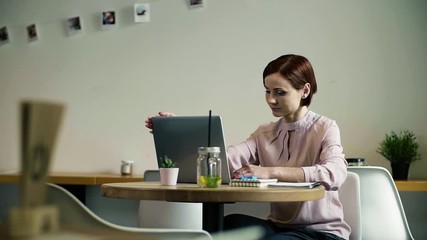 Wall Mural - A woman with laptop sitting at the table in a cafe. Slow motion.