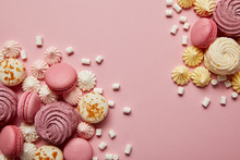 Smashed delicious sweet meringues, macaroons and small marshmallows pieces on pink background
