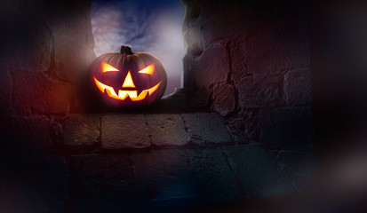 Wall Mural - the glowing evil stare of jack o latern on the ruins of an old church, monastery window at night.