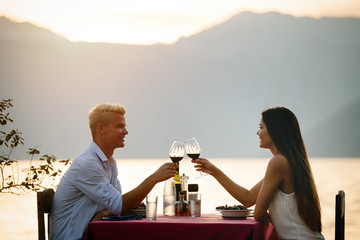 Young romantic couple toasting during dinner on tropical vacation