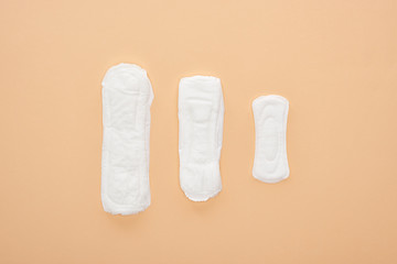 Wall Mural - top view of three white cotton sanitary towels isolated on beige