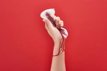 Partial View Of Woman Squeezing Sanitary Towel With Blood On Red Background