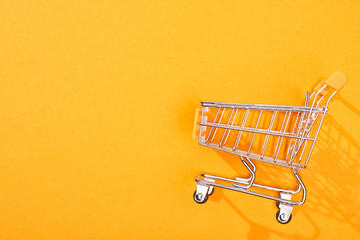 top view of empty shopping cart on bright orange background