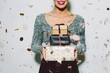 © Bonninstudio/Stocksy - Glamorous woman holding gifts in a New Year party celebration.